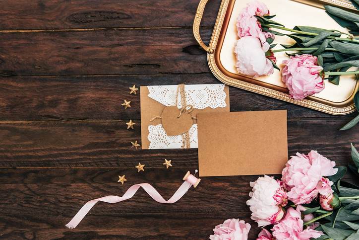 Mock up empty card with envelope and pink peony on vintage wooden background. Top view, copy space, wedding invitation concept