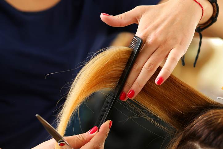Female hairdresser hold in hand lock of blonde hair